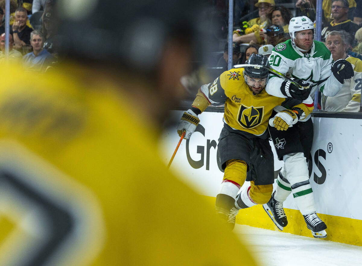 Golden Knights left wing William Carrier (28) drives Dallas Stars defenseman Ryan Suter (20) in ...