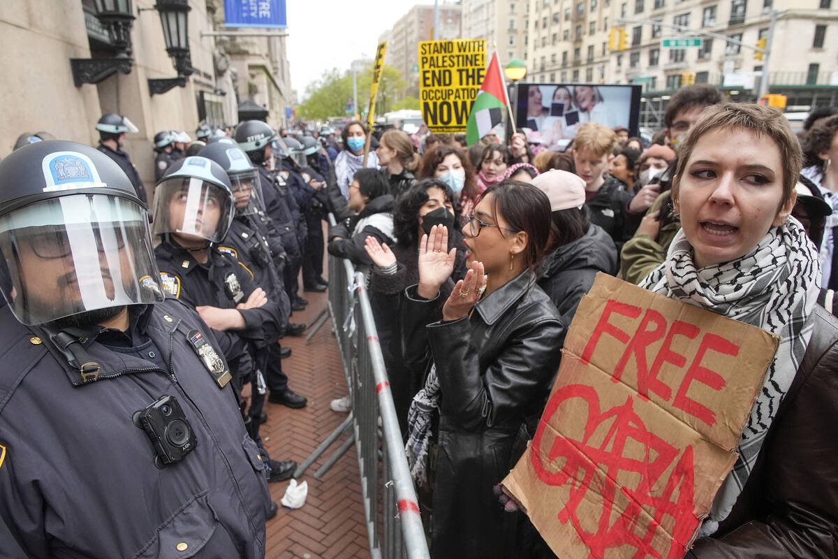 Police in riot gear stand guard as demonstrators chant slogans outside the Columbia University ...