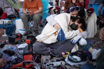Pro-Palestinian demonstrators embrace while charging devices at an encampment on the UCLA campu ...
