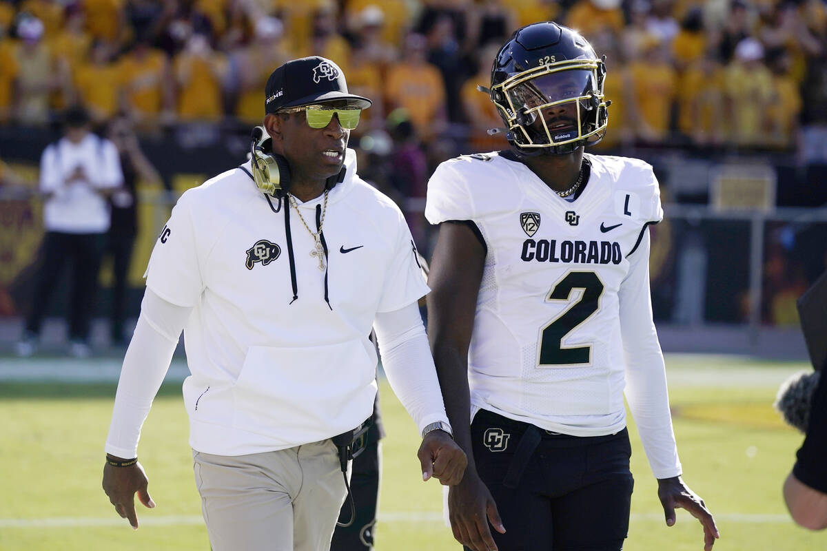 Colorado head coach Deion Sanders, left, talks with his son and starting quarterback Shedeur Sa ...