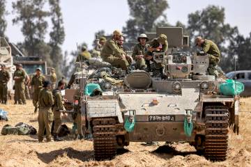 Israeli soldiers sit atop an infantry fighting vehicle (IFV) positioned near the border with th ...