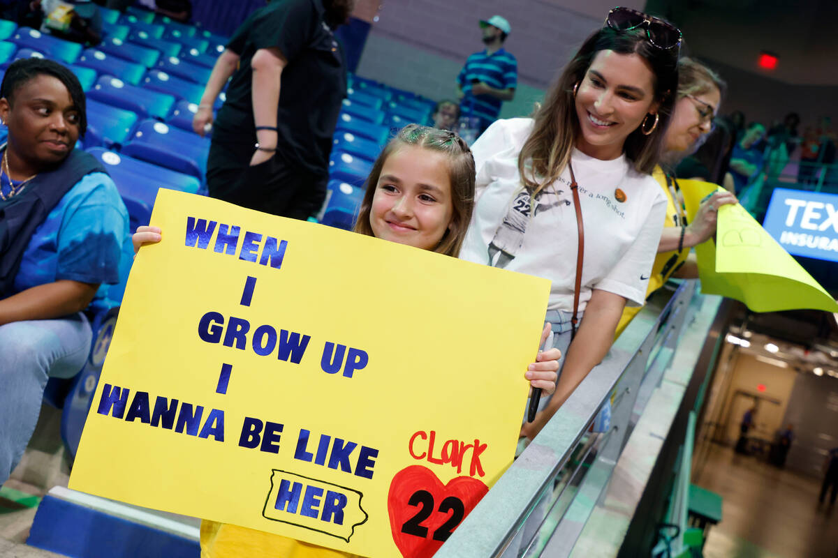 Pailynn Amos, center, holds a sign for Indiana Fever guard Caitlin Clark in front of her mother ...