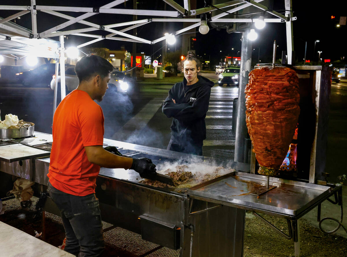 Marley Webster watches as Jaime Melendez prepares his tacos at his taco stand at the corner of ...