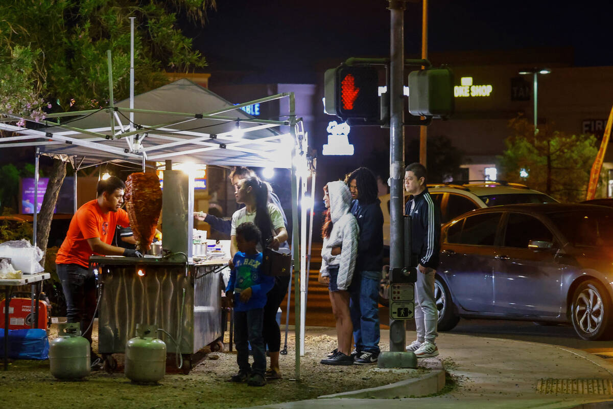 Jaime Melendez, left, prepares tacos al pastor at his taco stand at the corner of Durango Drive ...