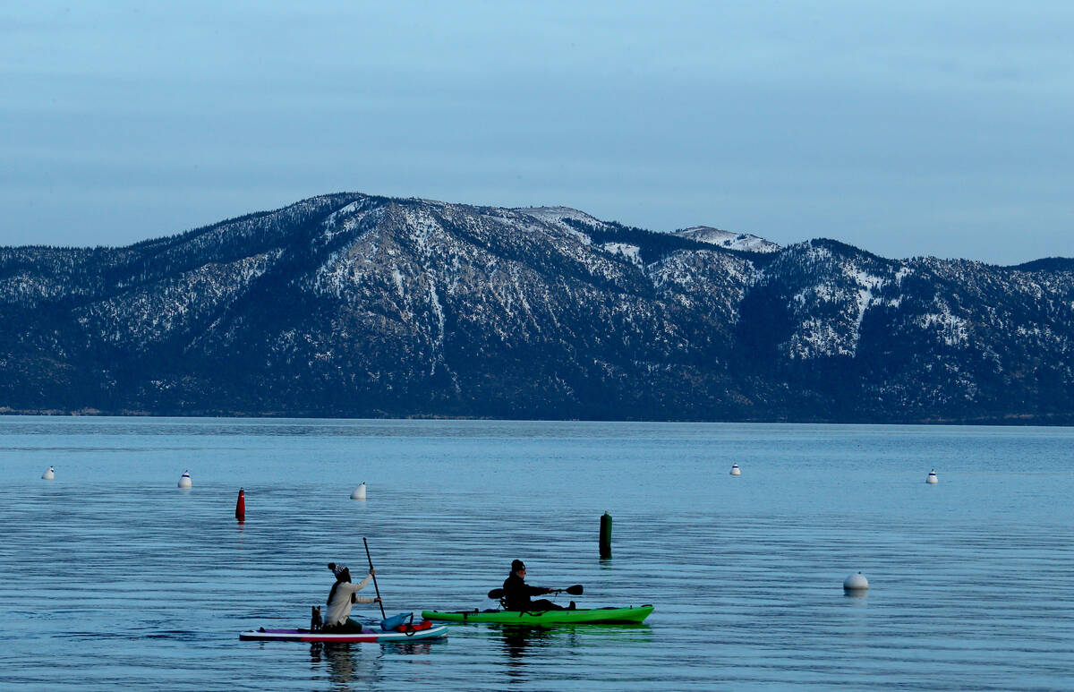 A paddle boarder and a kayaker glide across the surtface of Lake Tahoe's frigid waters on Jan. ...