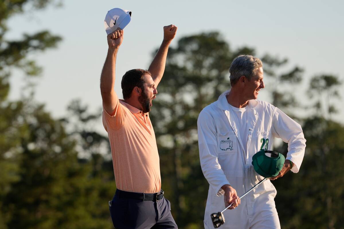 Scottie Scheffler celebrates with his caddie Ted Scott after winning the Masters golf tournamen ...