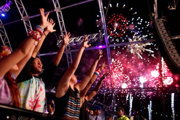 Jaime Yoo, in tie-dyed shirt, dances with others as fireworks erupt over the Electric Daisy Car ...