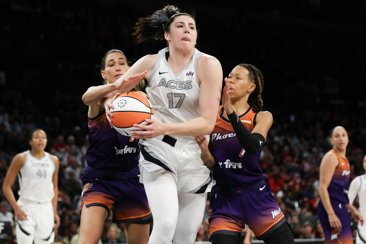 Las Vegas Aces center Megan Gustafson (17) snags a rebound with pressure from Phoenix Mercury g ...