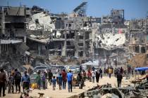 People move past destroyed buildings along a street in Khan Yunis in the southern Gaza Strip on ...