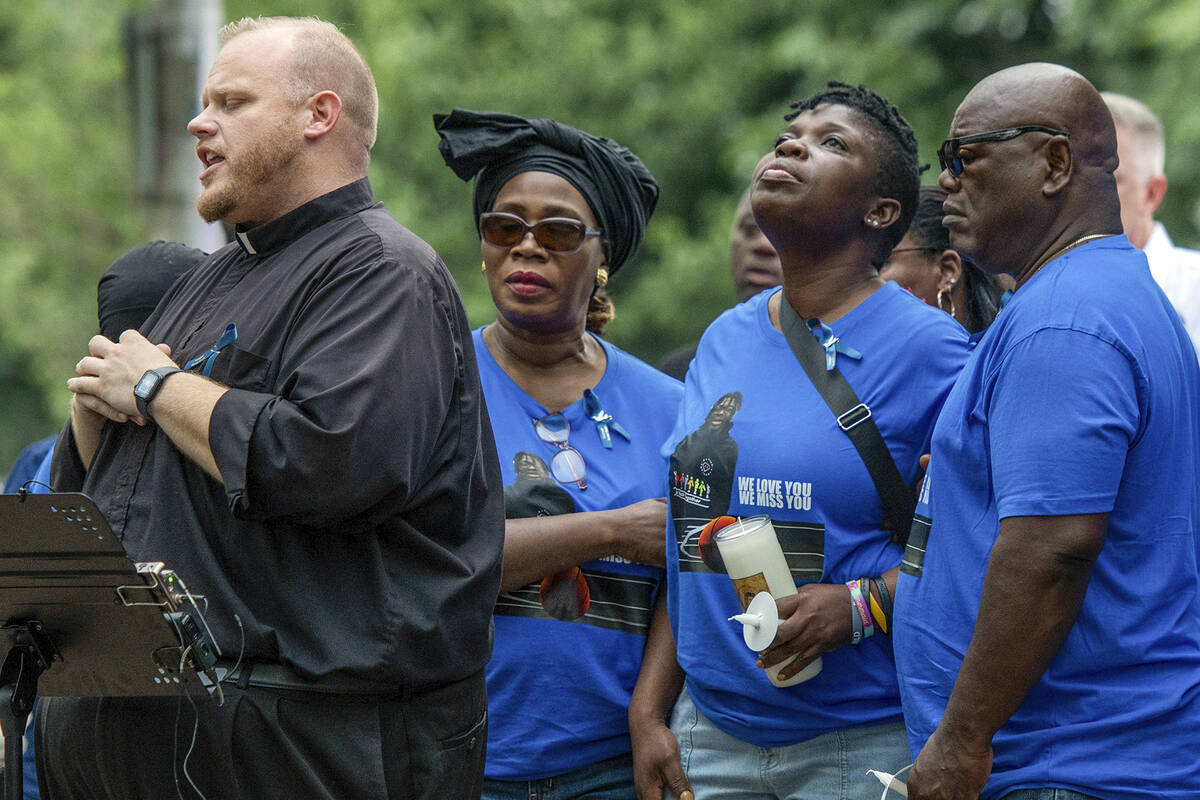 Rev. Jonathan Slavinskas, left, prays with the family of Harris Wolobah, including mother Lois ...