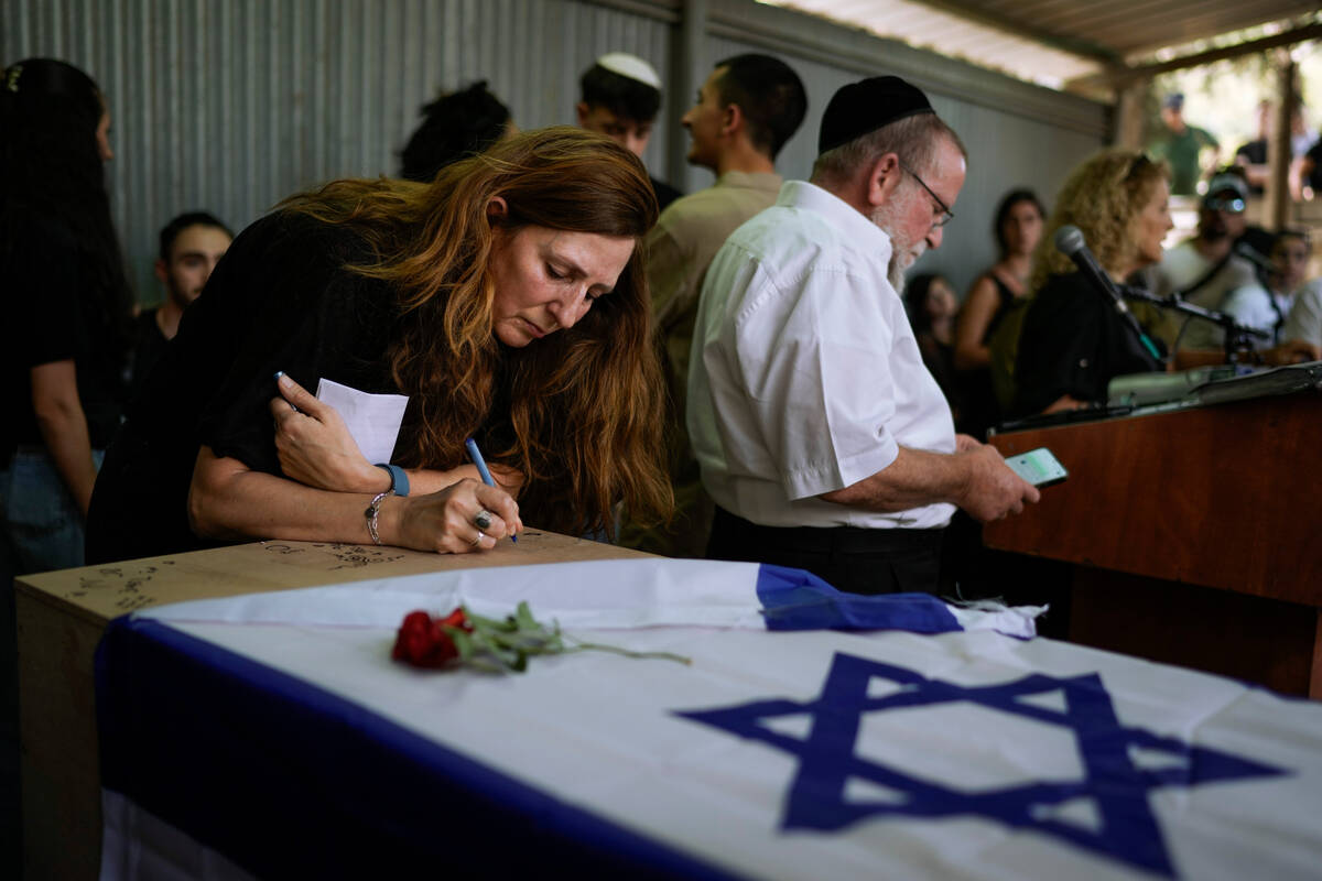 Ricarda Louk, writes on the flag-covered coffin of her daughter Shani Louk during her funeral i ...