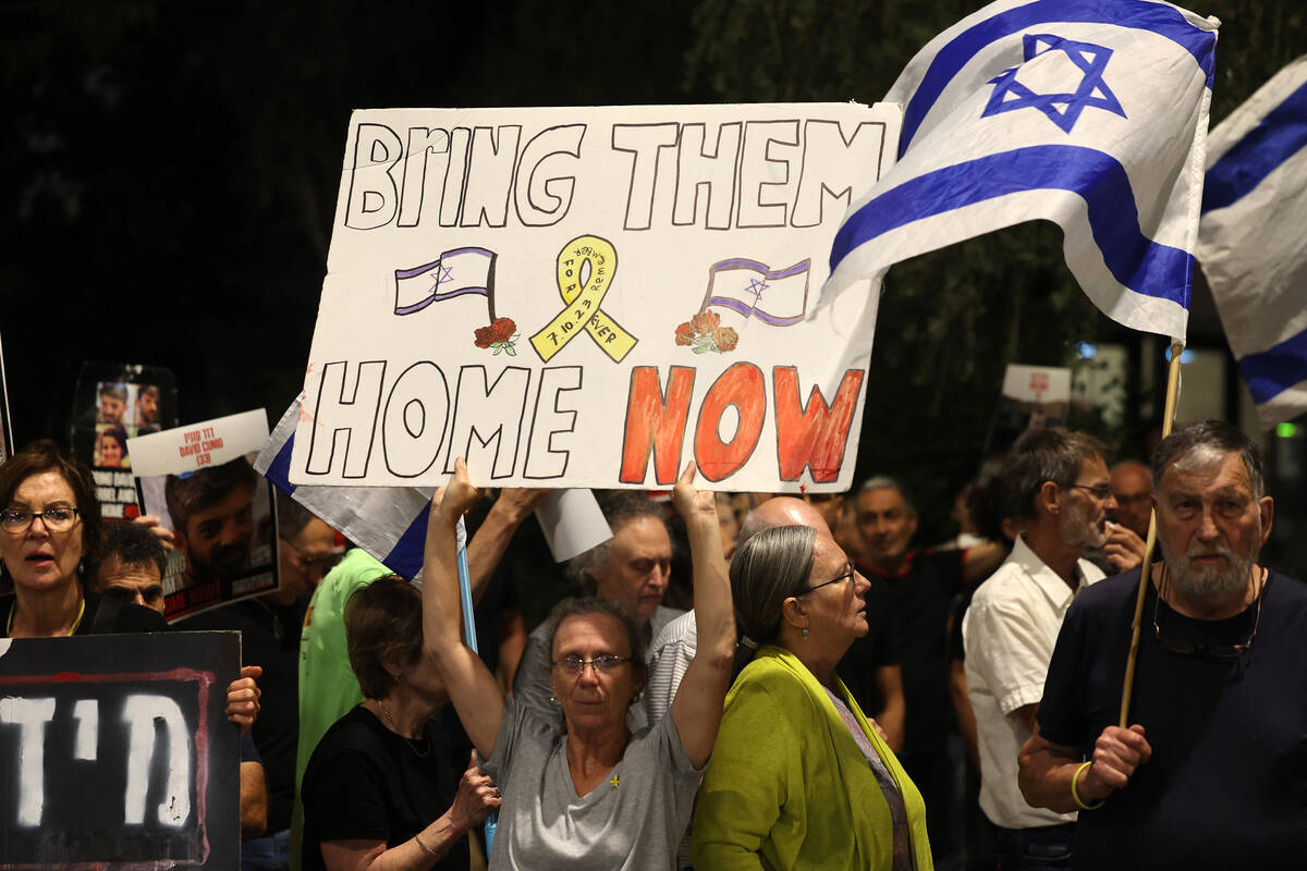 Relatives and supporters raise placards bearing messages and portraits of Israeli hostages held ...