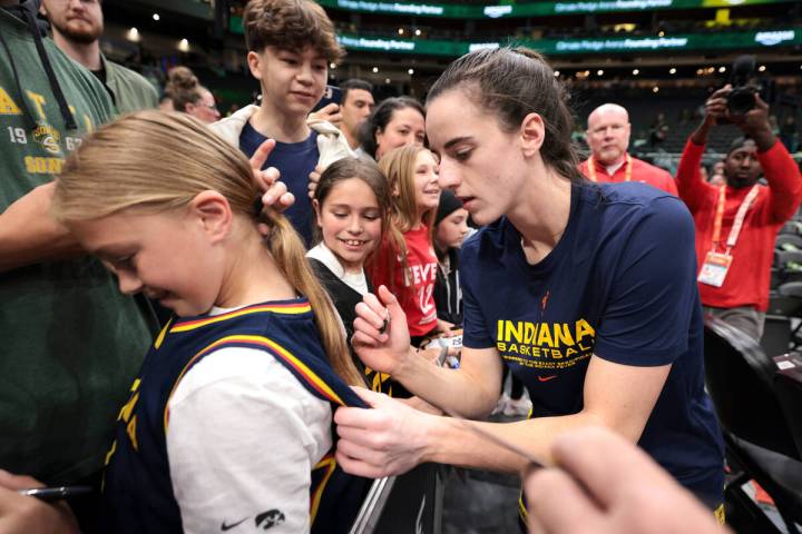 Indiana Fever guard Caitlin Clark, right, signs autographs before the team's WNBA basketball ga ...