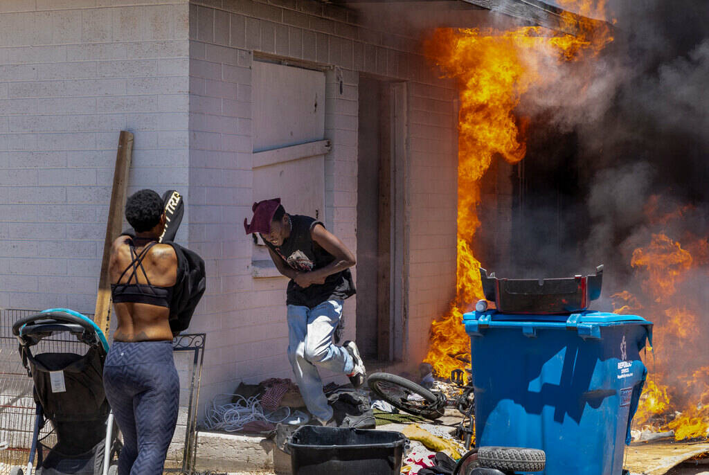 A man runs out from a burning house after going back inside to check on others during a fire be ...