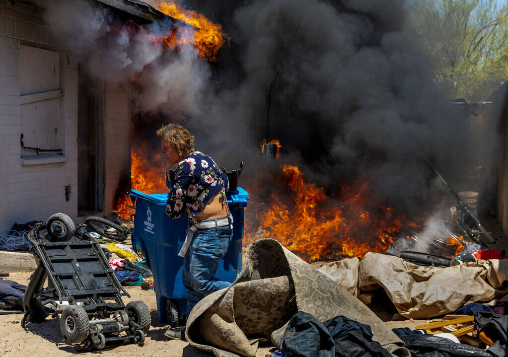 A woman pulls items away from a burning house during a fire between W. Jefferson Ave. and W. Ad ...