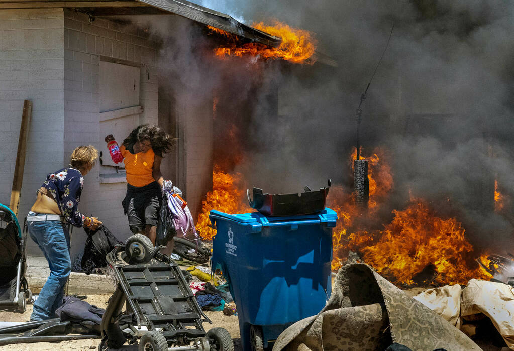 A woman runs out from a burning house during a fire between W. Jefferson Ave. and W. Adams Ave. ...