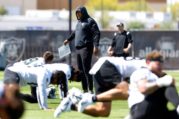 Raiders head coach Antonio Pierce watches his players stretch during team's practice at the Int ...