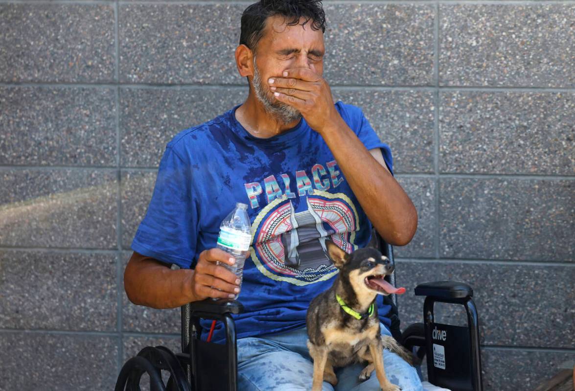 Polly sits on her owner Daniel Zamora's lap as he cools himself with water during a hot day at ...
