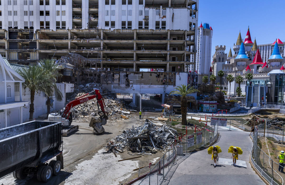 Showgirls carry hydration as they pass by the Tropicana demolition as workers there use protect ...