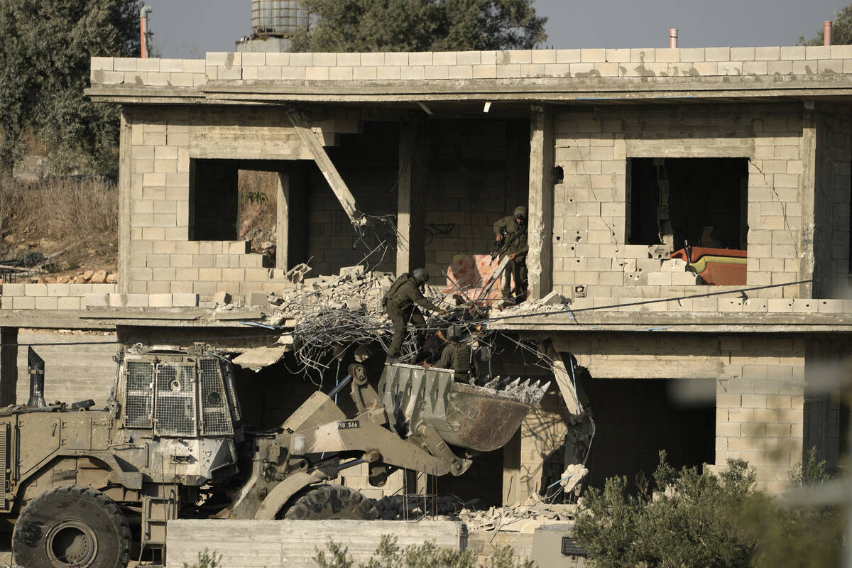 FILE - Israeli forces remove a body of a man killed during a military operation in the West Ban ...