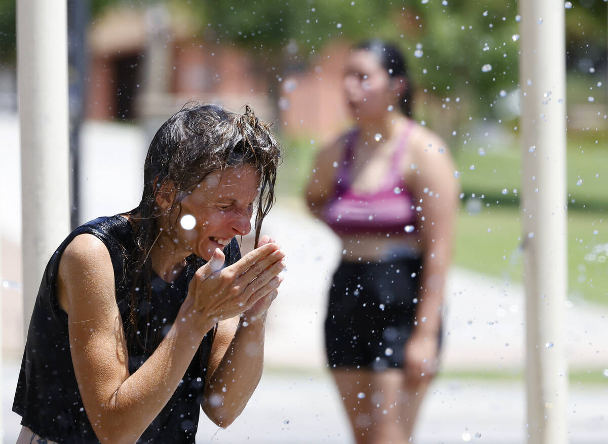 People, including Jeanette Juraska, left, of Las Vegas cool themselves in the splash pad at Lor ...
