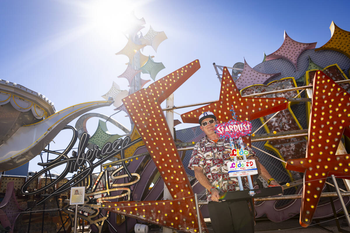 Chris Raley, of Route 9 Signs, based out of Fresno, Calif, poses with his miniature replica nex ...
