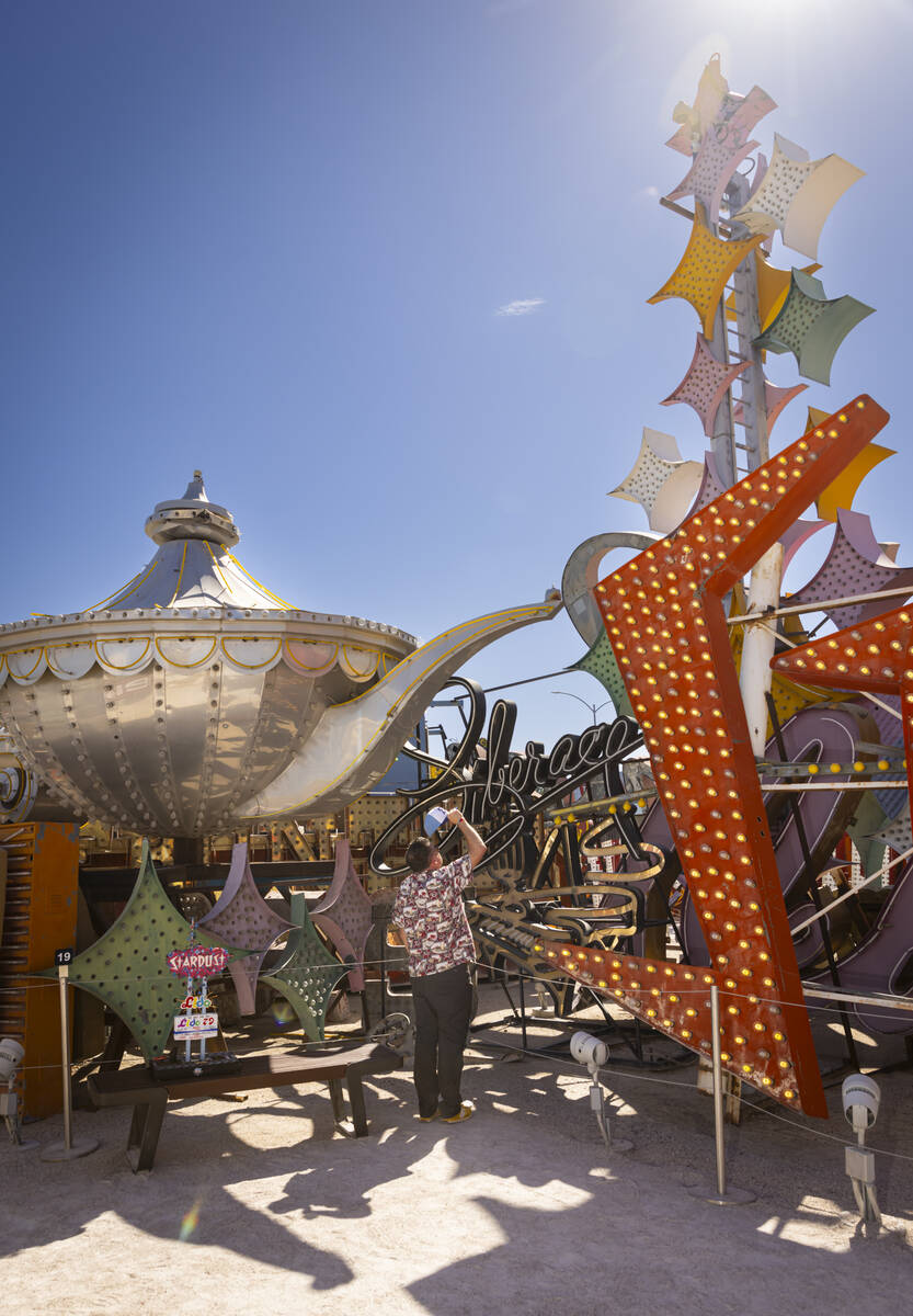 Chris Raley, of Route 9 Signs, based out of Fresno, Calif, looks up at parts of the Stardust ma ...
