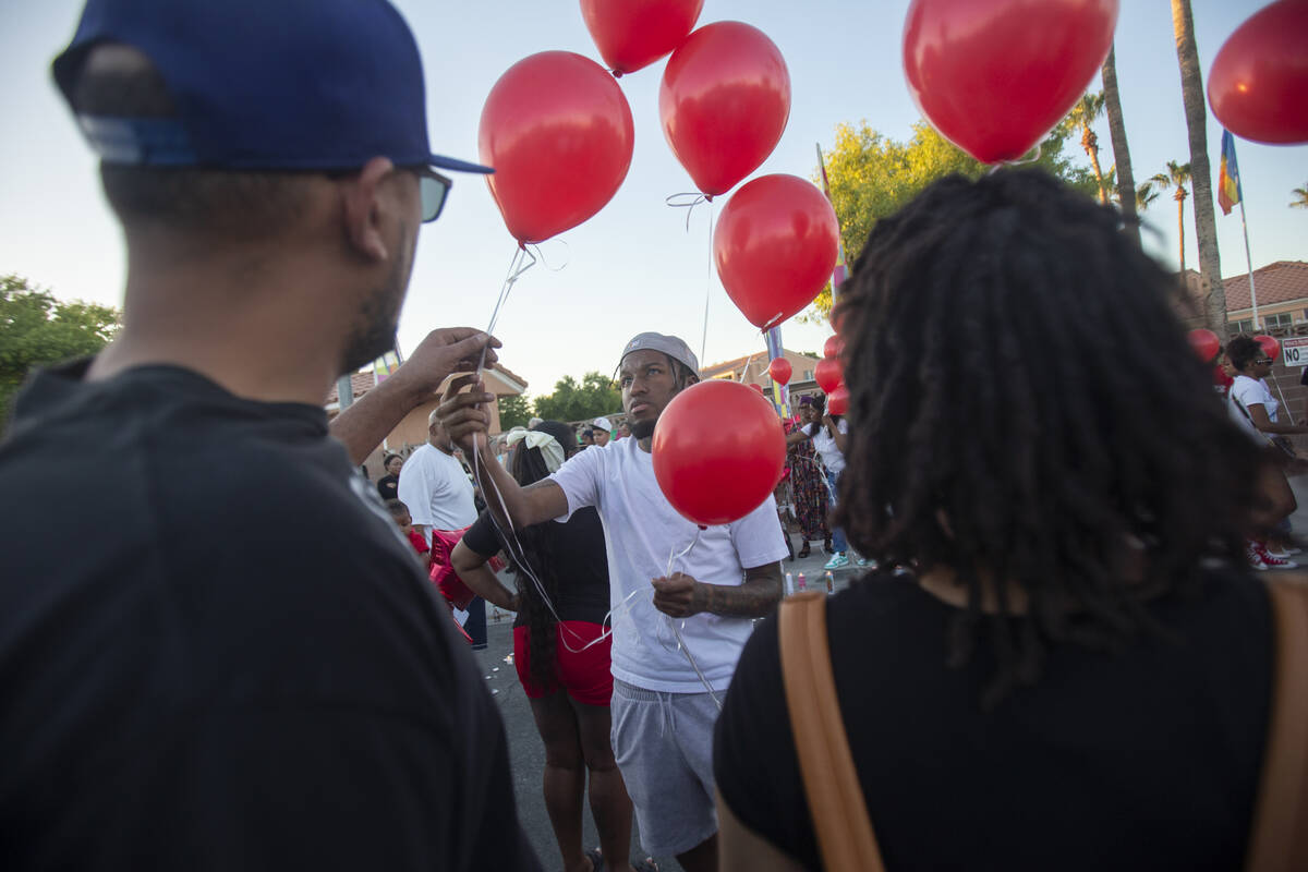 Red balloons are handed out during a candlelight service for Kayla Harris at Craig Ranch Villas ...