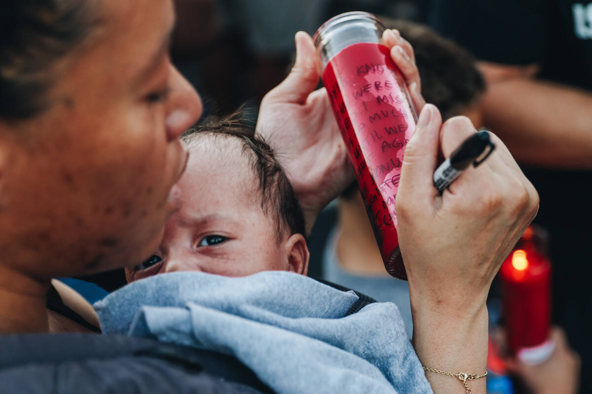 A mourner writes a message on a prayer candle during a vigil for Kayla Harris, who was killed i ...