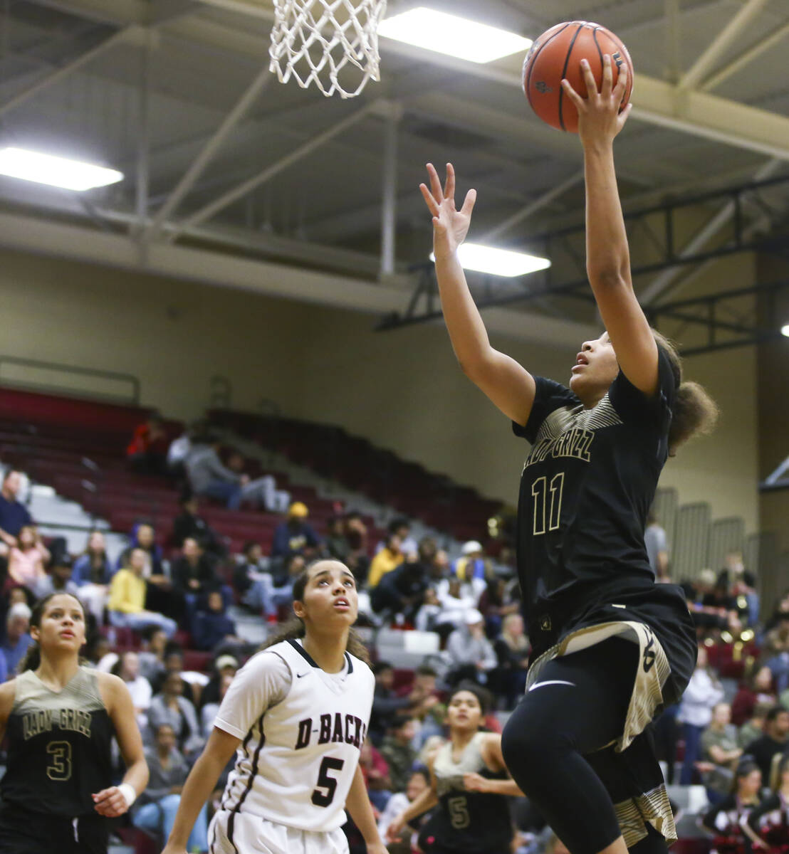 Spring Valley's Kayla Harris (11) goes to the basket over Desert Oasis' Eliyjah Pricebrooks (5) ...