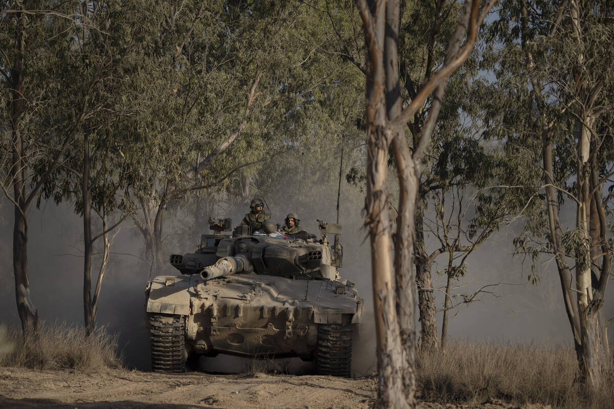 Israeli soldiers move on the top of a tank near the Israeli-Gaza border, as seen from southern ...