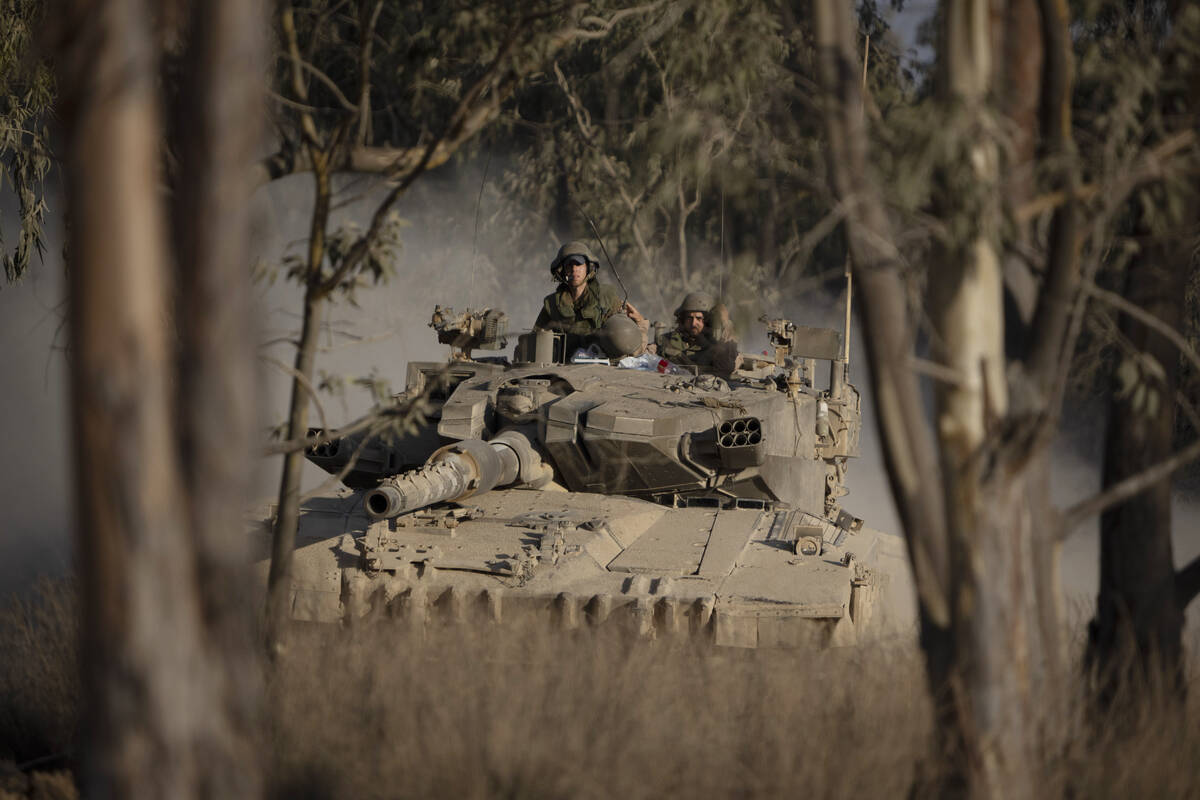 Israeli soldiers move on the top of a tank near the Israeli-Gaza border, as seen from southern ...