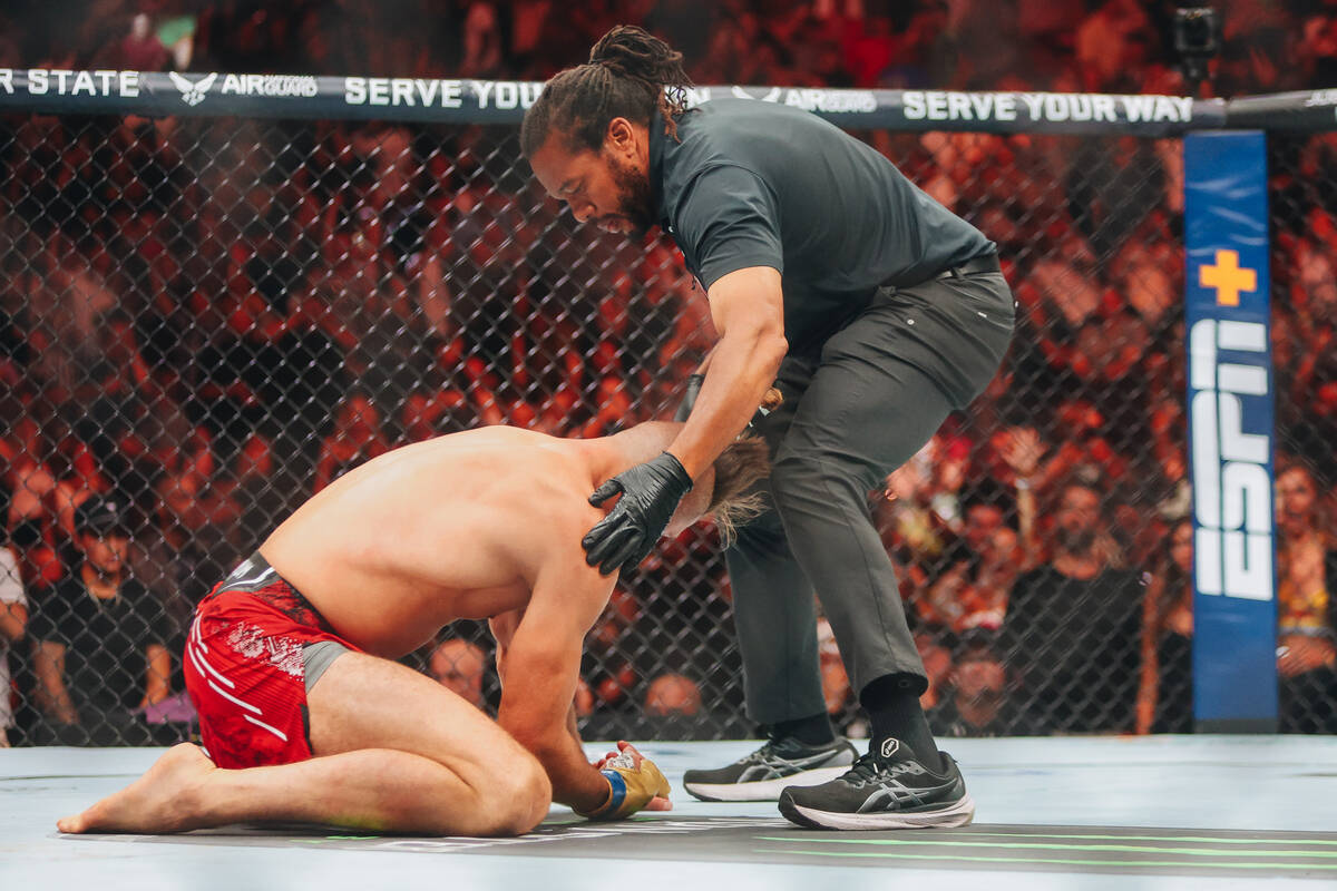 A referee checks on Jiri Prochazka during a light heavyweight title bout against Alex Pereira a ...