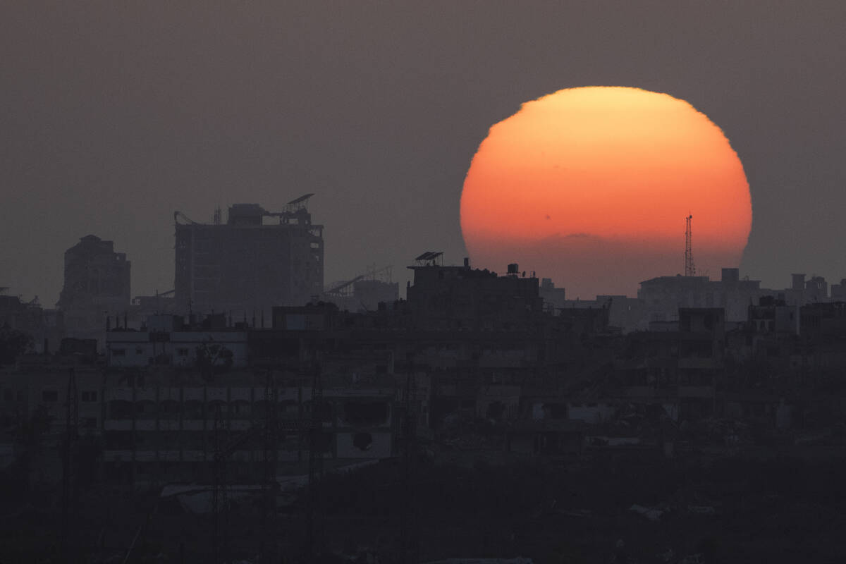 The sun sets behind the buildings in the Gaza Strip as seen from southern Israel, Saturday, Jun ...