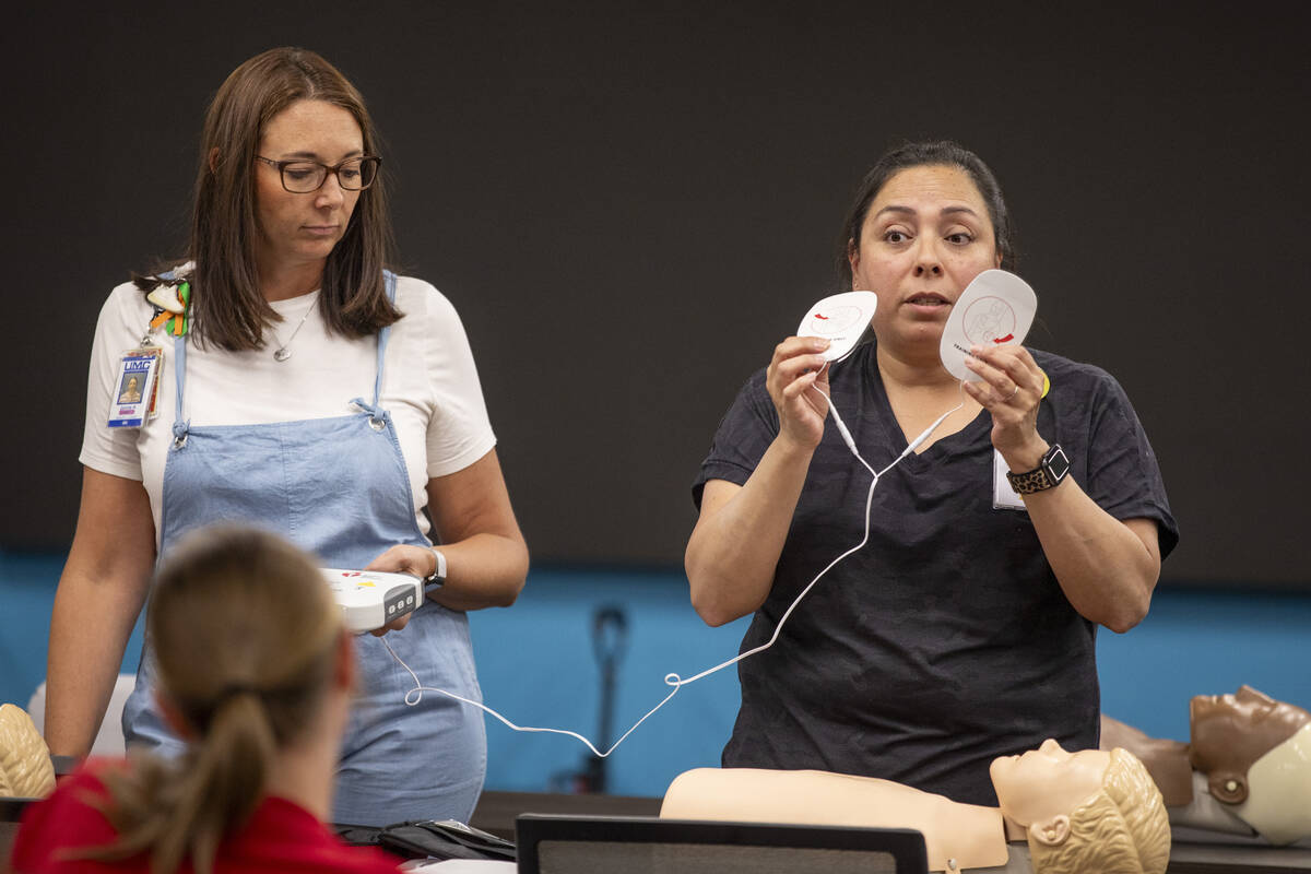 R.N. Jamie Hurley, left, and R.N. Xochitl Kambak, right, teach campers on how to use an automat ...
