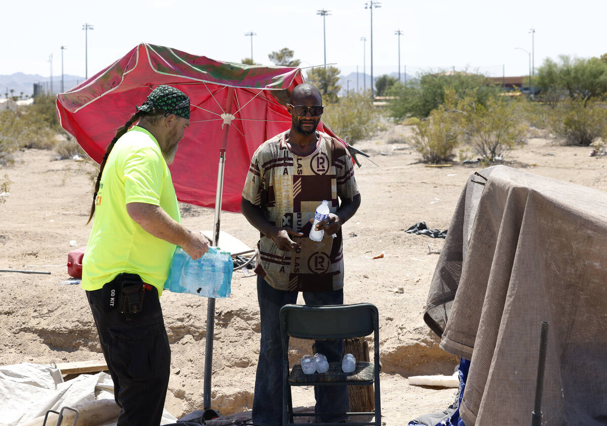 Chris Engel, a Help of Southern Nevada outreach worker, delivers a case of water to Erik Smith, ...