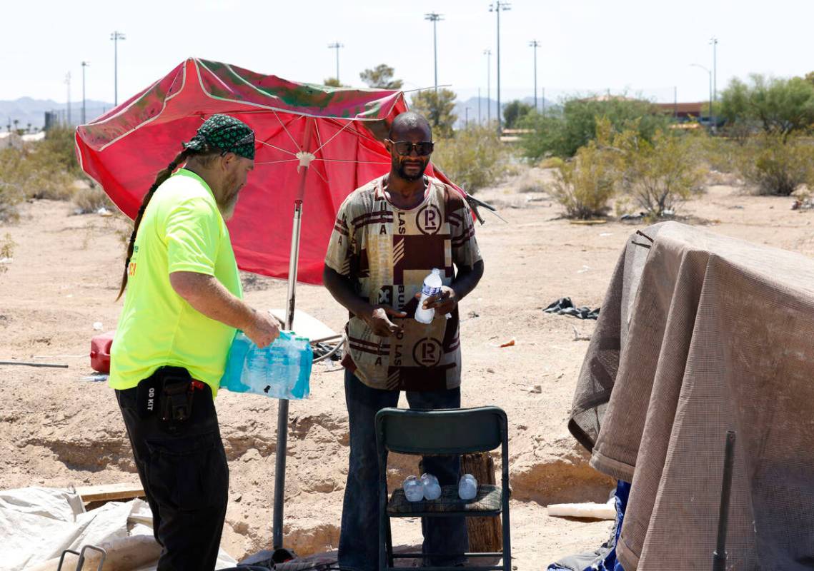 Chris Engel, a Help of Southern Nevada outreach worker, delivers a case of water to Erik Smith, ...