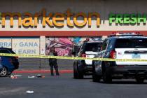 Metropolitan Police Department officers investigate a taped-off scene at a shopping center park ...