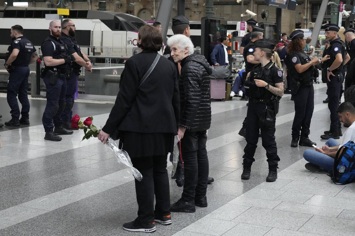 Travelers wait inside the Gare du Nord train station as police officers patrol at the 2024 Summ ...