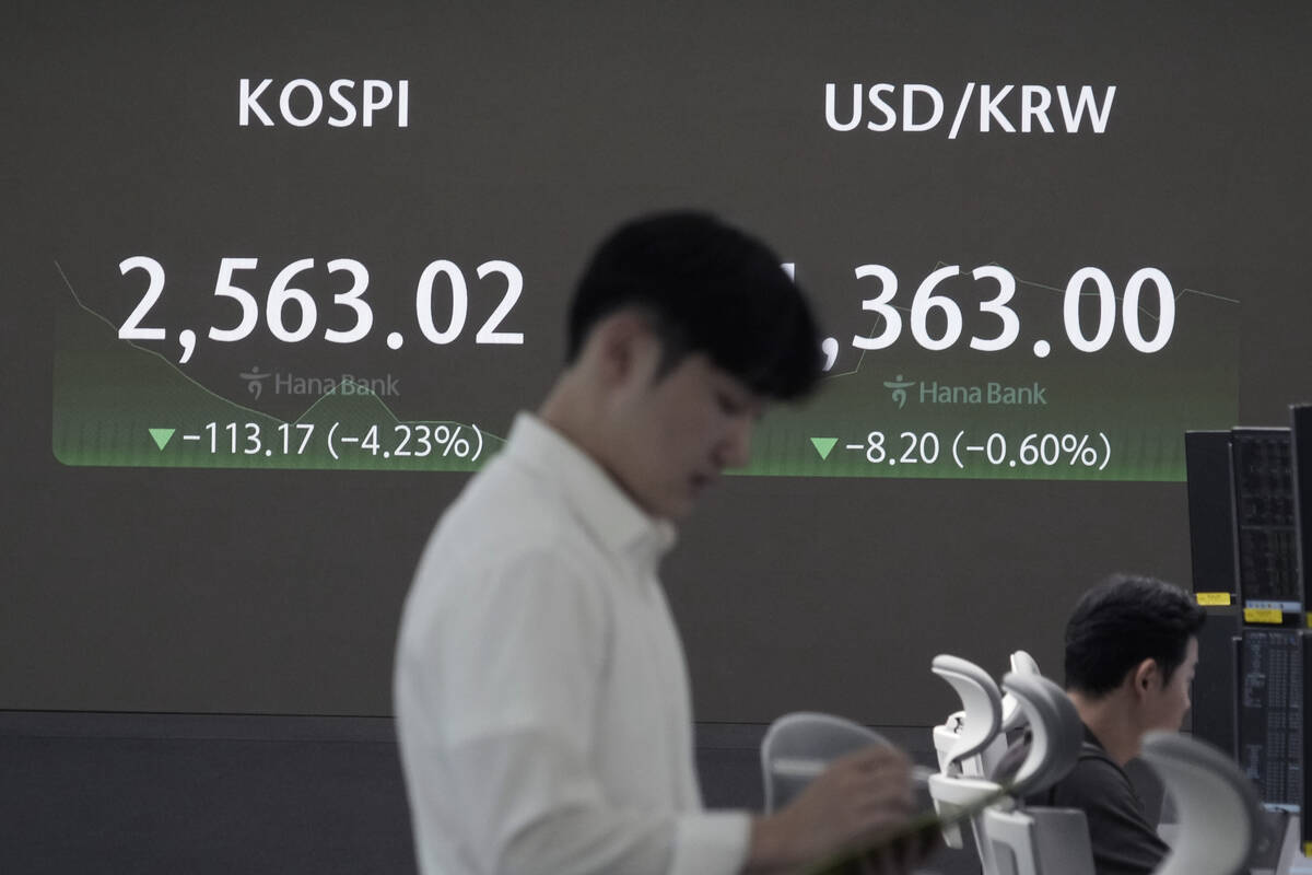 A currency trader works near a screen showing the Korea Composite Stock Price Index (KOSPI), le ...