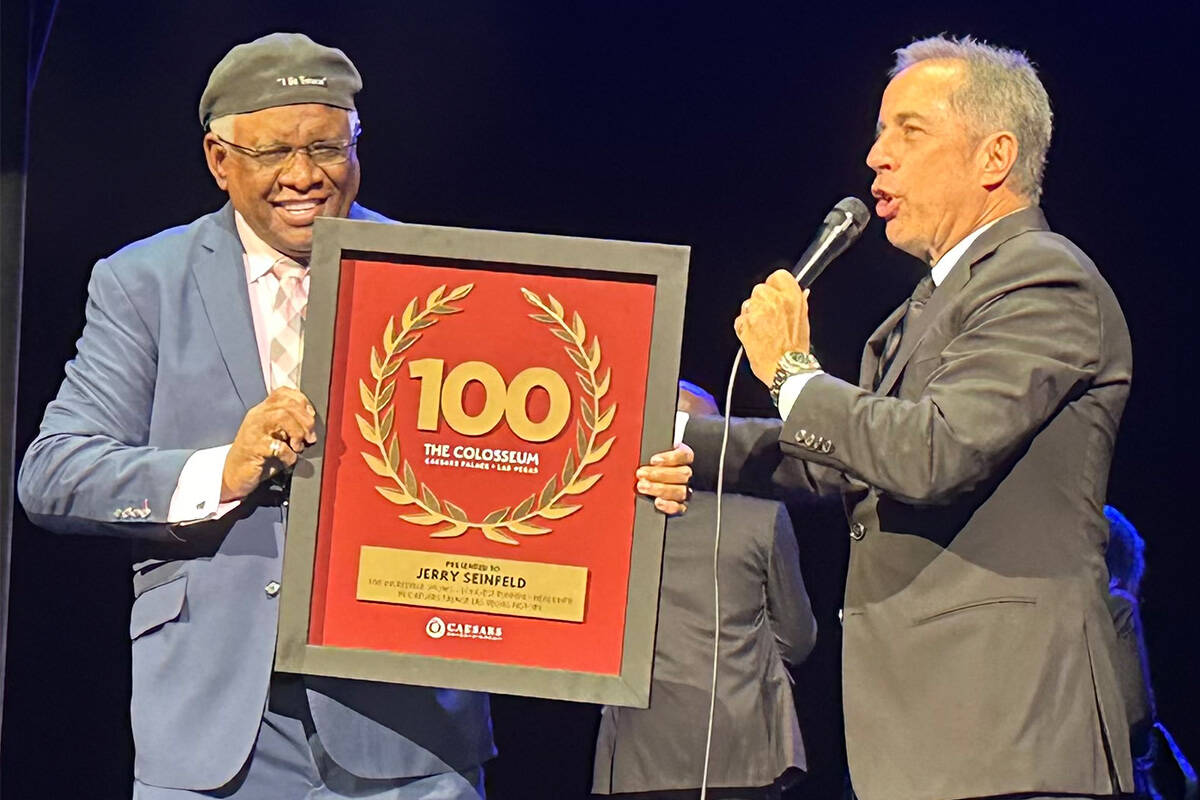 George Wallace presents Jerry Seinfeld with a plaque commemorating Seinfeld's 100th performance . 