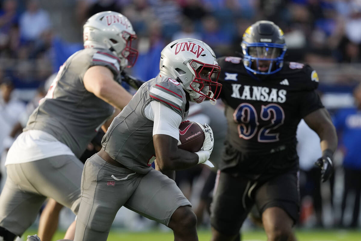 UNLV running back Jai'Den Thomas, center, runs the ball against Kansas in the first half of an ...