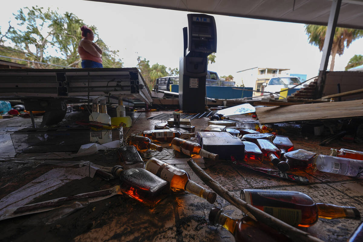 Kegan Ward, assistant manager of Swami Spirits, walks through debris of the damaged store in th ...