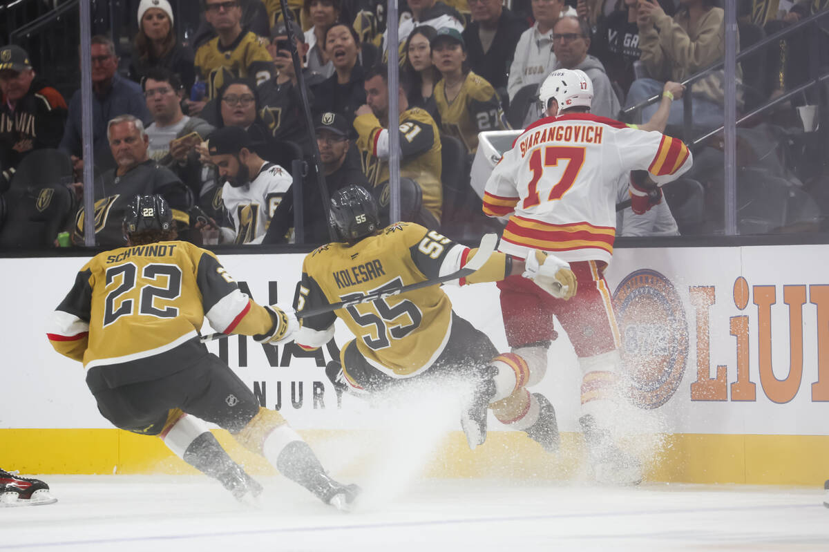 Golden Knights right wing Keegan Kolesar (55) gets tripped up between Calgary Flames center Yeg ...
