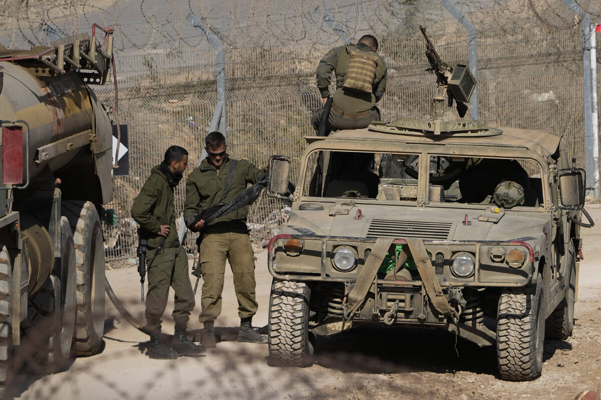 Israeli soldiers stand next to armoured vehicles after crossing the security fence, near the so ...