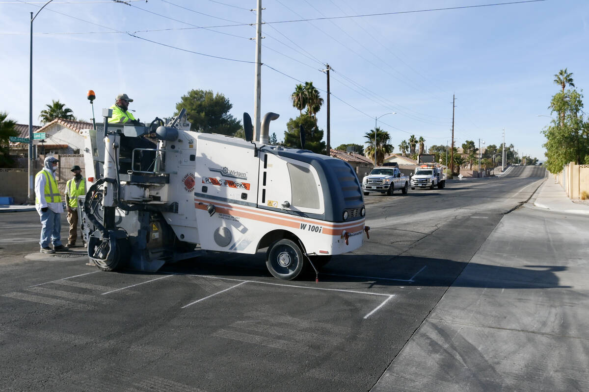 Workers from Clark County Public Works mill the road at the intersection of Lamb Boulevard and ...