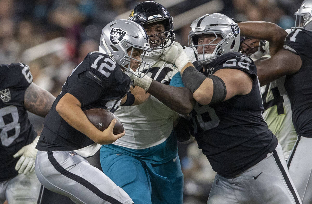 Raiders quarterback Aidan O'Connell (12) escapes pressure as guard Jackson Powers-Johnson (58) ...