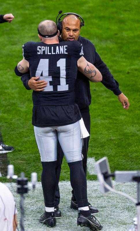 Raiders head coach Antonio Pierce and linebacker Robert Spillane (41) hug on the sideline befor ...
