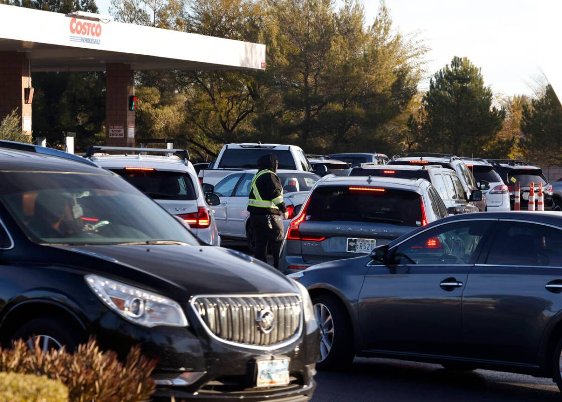 An employee directs traffic as people line up at a Costco gas station in Summerlin, on Friday. ...