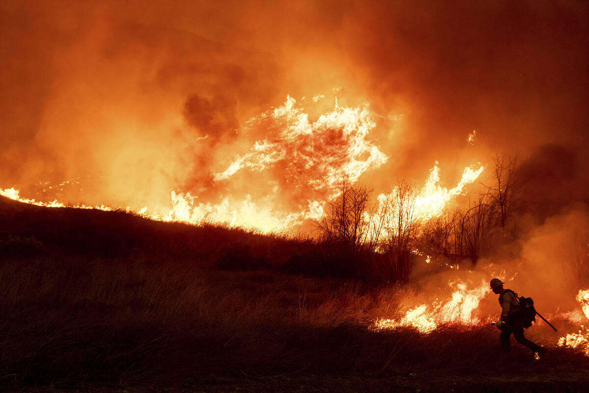 A firefighter sets a backburn in front of the advancing Kenneth Fire in the West Hills section ...
